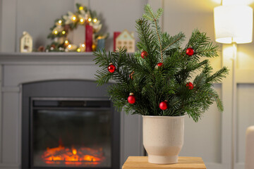 Beautiful Christmas composition of decorated fir tree branches on stool indoors