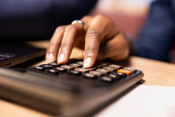 Fototapeta premium Black people working together on their taxes management at their home office, calculating deductions and ensuring financial stability for the coming year. Couple review savings. Close up.