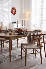Stylish table setting with beautiful dishware and autumn decor in dining room