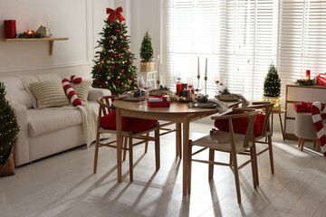 Christmas table setting with stylish dishware, glasses and burning candles in festive decorated room