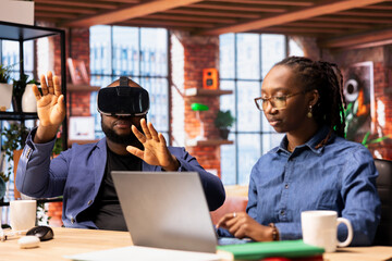 Black man embraces digital innovation at home office and uses VR headset for interactive experiences, while his wife works on business operations. Artificial intelligence and remote work balance.