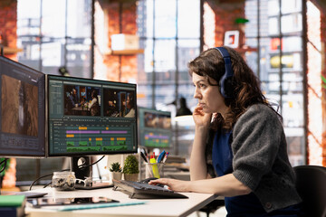 Young filmmaker woman working on video post production at creative agency office, mixing video...