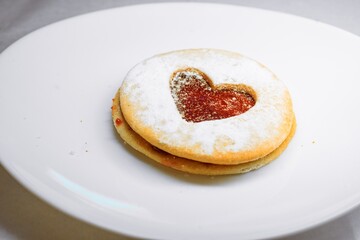 Heart-Shaped Linzer Cookie with Powdered Sugar on White Plate