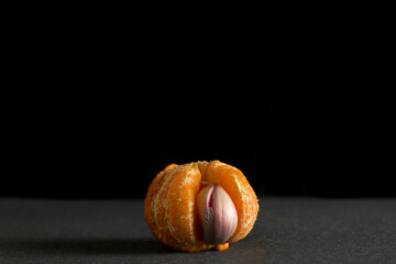 Concept being in the wrong place not fitting in head of garlic with a mandarin orange segment
