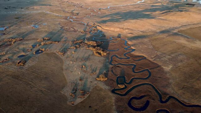 Kupresko polje or Kupres field, Bosnia and Herzegovina. The river flows meanderingly through the field. A winding river in nature, aerial drone view. Meander.