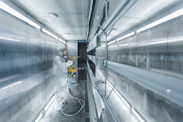 man painting parts in powder coating booth