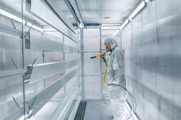 man painting parts in powder coating booth
