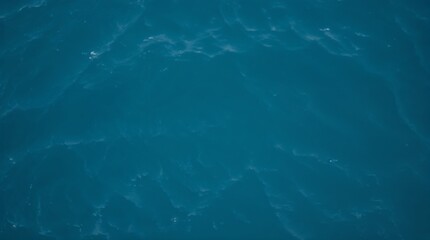 Aerial top view of ocean water surface with gentle waves in deep blue color  