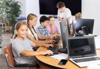 Fototapeta premium Happy underage girl engaged in IT training during computer courses for children