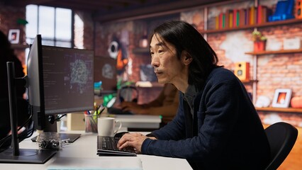 Software engineer in small business workspace using computer to oversee artificial intelligence...