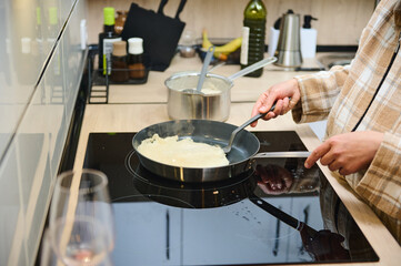 Person Cooking Crepes in a Modern Kitchen with Utensils and Ingredients