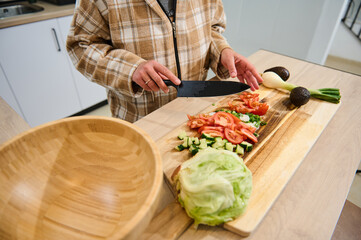 Person Preparing Fresh Salad with Vegetables in a Modern Kitchen