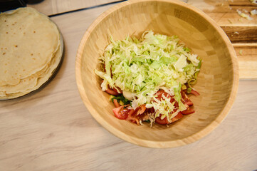 Fresh Salad in Wooden Bowl Next to Homemade Tortillas on Kitchen Table