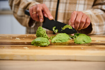 Woman Preparing Avocado and Salad Ingredients on Wooden Cutting Board