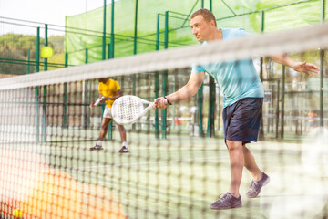 Caucasian man in sportswear playing padel tennis match during training on court.