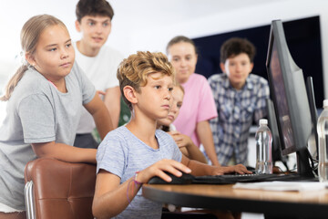 Group of children students learning to use computer in classroom