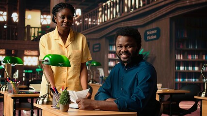 Students team read through an academic project in a classic library, showcasing their commitment to education and self improvement. Black pupils work together on their academic growth. Camera A.