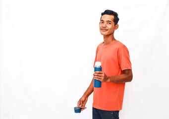 A Smiling Man Posing with a Thermos and a Cup Against a Plain Background