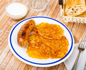 Fried grated potato pancakes served with sausage and sour cream