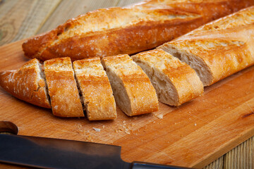 Closeup of cut fresh french baked baguettes on wooden desk, nobody