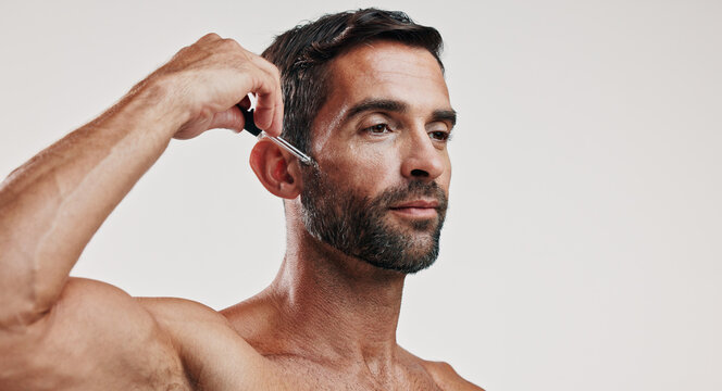 Hands, man and serum for skincare in studio for beard oil, facial treatment and dermatology cosmetics. Person, product and collagen for hair growth, hyaluronic acid and anti aging on white background