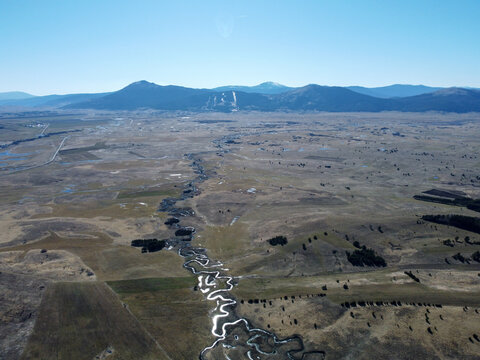 Kupresko polje or Kupres field, Bosnia and Herzegovina. The river flows meanderingly through the field. A winding river in nature, aerial drone view. Meander.