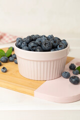 Bowl with fresh bright blueberries on wooden table