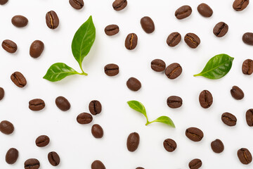 Roasted coffee beans with leaves on white background,top view