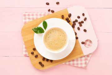 Cup of coffee with coffee beans and leaves on wooden background,top view