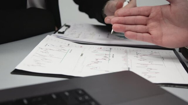 Two businessmen brainstorming with charts, papers, and a computer. Concept effective teamwork, strategy planning, and small business startup growth in an office environment.