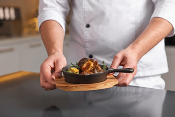 Professional chef serving dish at table indoors, closeup