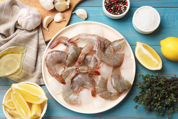 Fresh raw shrimps, ice cubes and spices on light blue wooden table, flat lay