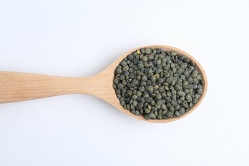 Raw lentils in wooden spoon isolated on white, top view