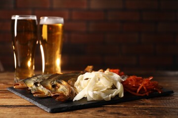 Different dried fish snacks and beer on wooden table