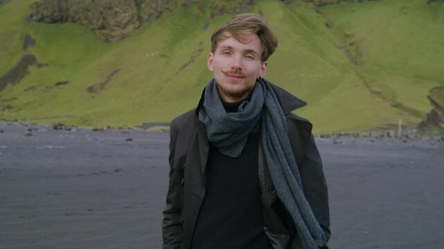 Smiling caucasian man joyfully stands on Reynisfjara beach in South Iceland, surrounded by a stunning landscape that showcases the beauty and uniqueness of this remarkable travel destination