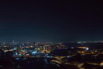 Aerial view of Abu Dhabi at night, showcasing the city's illuminated skyline, modern skyscrapers, and roads glowing under the night sky.