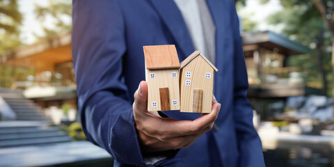 Professional holding miniature houses illustrating real estate concepts