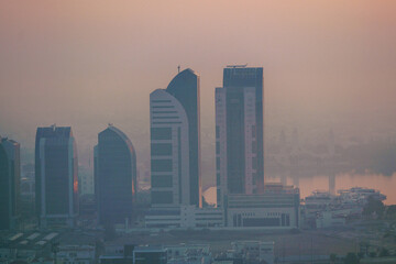 Aerial view of Abu Dhabi in the morning light, as the rising sun casts a golden glow over the city's modern skyline.