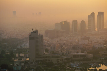 Aerial view of Abu Dhabi in the morning light, as the rising sun casts a golden glow over the city's modern skyline.
