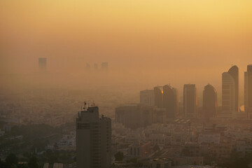 Aerial view of Abu Dhabi in the morning light, as the rising sun casts a golden glow over the city's modern skyline.