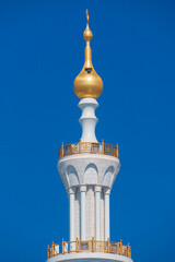 Close-up of the Sheikh Zayed Grand Mosque, showcasing its intricate white marble domes and elegant architectural details against a vivid blue sky. 