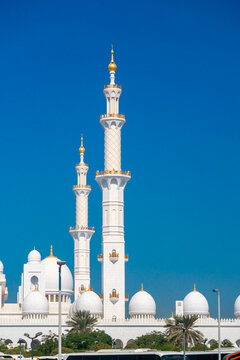 Close-up of the Sheikh Zayed Grand Mosque, showcasing its intricate white marble domes and elegant architectural details against a vivid blue sky. 