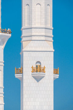 Close-up of the Sheikh Zayed Grand Mosque, showcasing its intricate white marble domes and elegant architectural details against a vivid blue sky. 