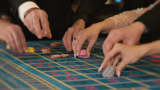 Hands of gambling people, men and women, betting chips in a casino. Casino concept. People playing in a casino. Big bets. Hands of people betting chips on a gambling table in a casino.