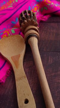 Utensilios de cocina de madera, cuchara y molinillo, con mantel mexicano rosado  sobre mesa de madera