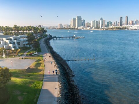 People enjoy outdoor recreation along the  Bayshore Bikeway waterfront path in Coronado, California, USA. The San Diego skyline is visible across the bay.