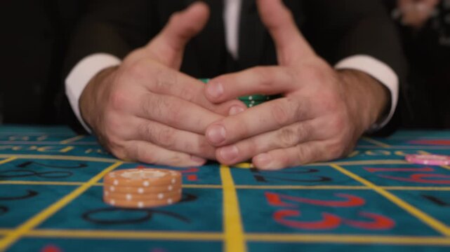 Casino player hands with poker chips on green table. Gambling and betting concept.
