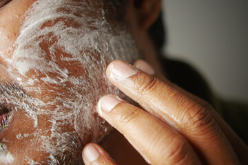 Man applying cleansing product on facial skin during morning routine