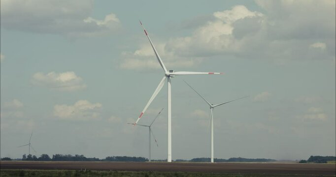 Wind turbines rotating blades in agricultural landscape