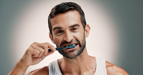 Dental, portrait and man brushing teeth on studio background for oral hygiene and fresh breath....